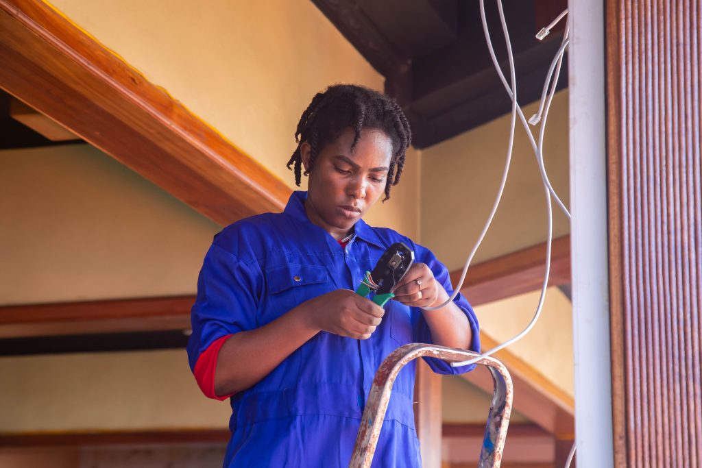 Programmes Professional electrician working on wiring in an indoor setting, demonstrating skill and concentration.