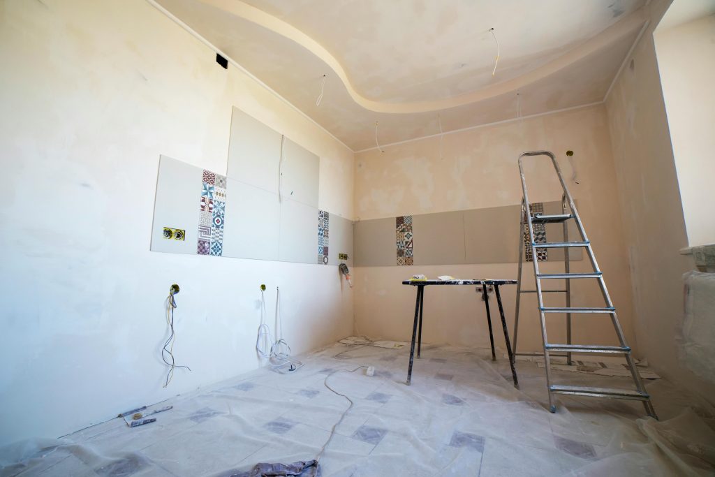 Programmes Interior view of a room under renovation with paint, tiles, and tools.